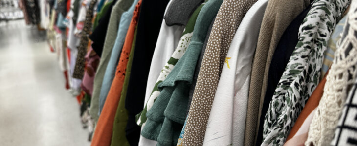 a rack filled with various clothing items in different colors and textures, hanging in a retail store