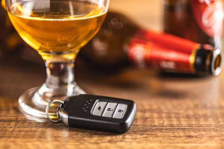Car key with beer glass on a wooden table. Booze driving concept. Drunk driver concept.