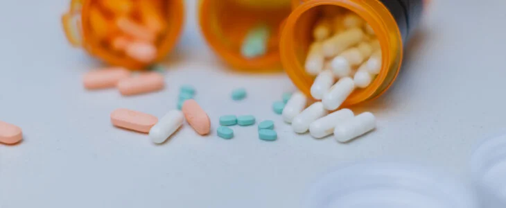 Part of daily life routine for an adult with ADHD, taking the right medication that helps them focus on daily life and achieve their goals throughout the day. These ADHD pills and other medicines are displayed with open pill bottles on top of a white counter top in the kitchen.