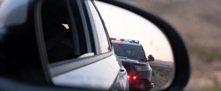 View from the passenger seat rear view mirror of getting pulled over by a police car
