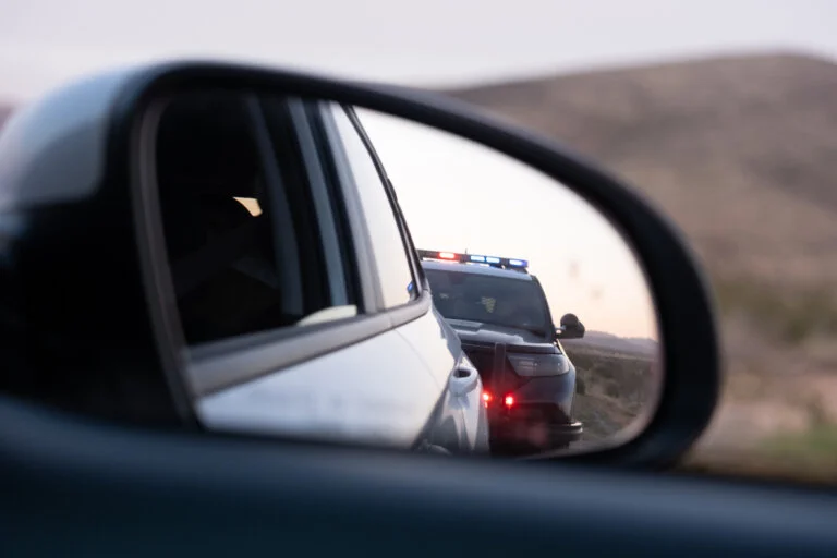 View from the passenger seat rear view mirror of getting pulled over by a police car